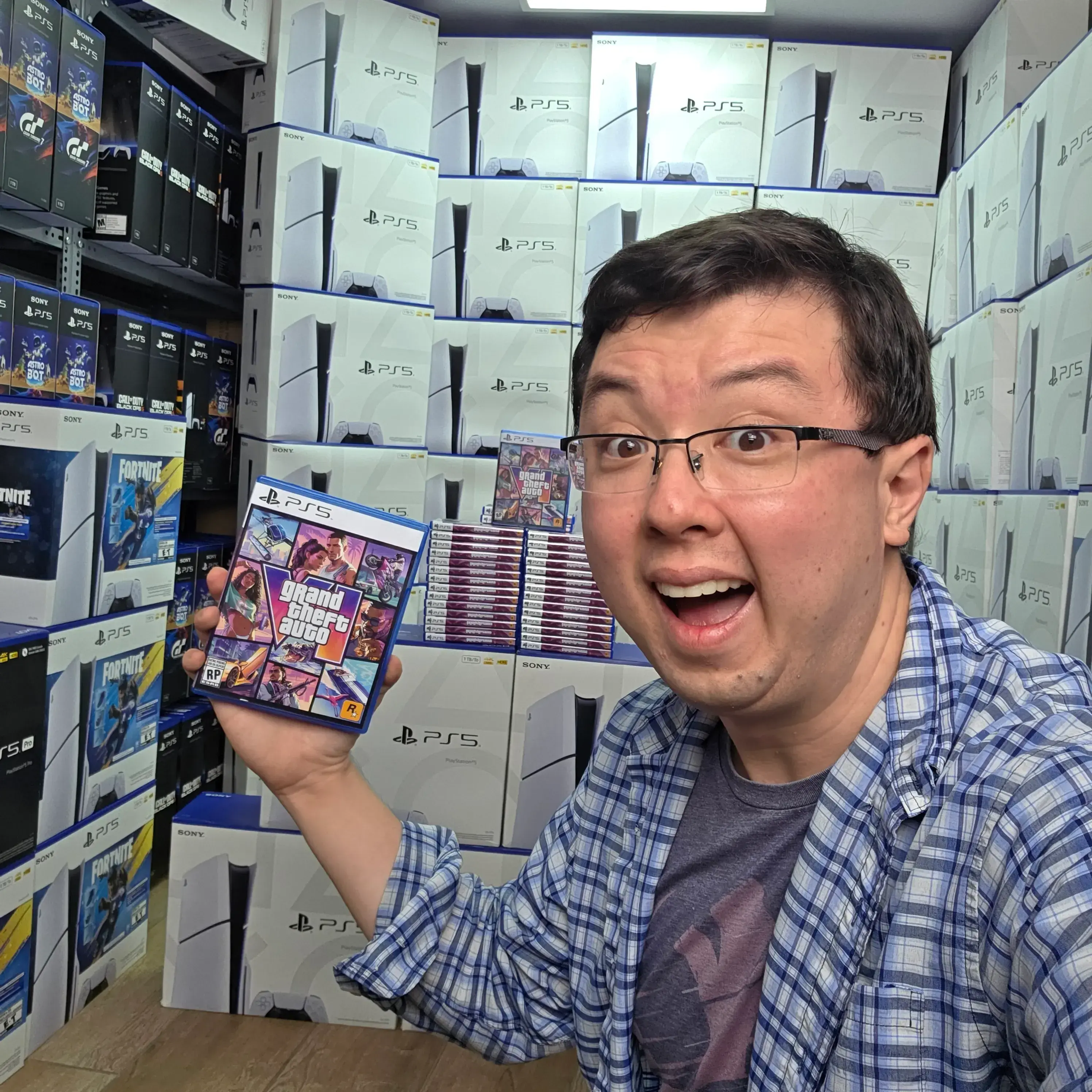 Phillip Chu Joy holding a video game in front of stacked PlayStation 5 consoles.